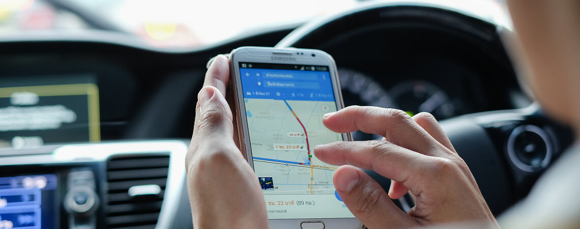 Frau nutzt Google Maps auf Smartphone im Auto