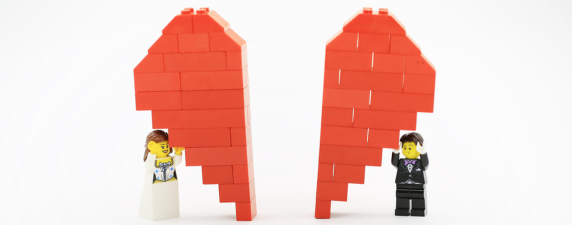 Geteiltes Lego-Herz, was von Braut und Bräutigam gestützt wird.