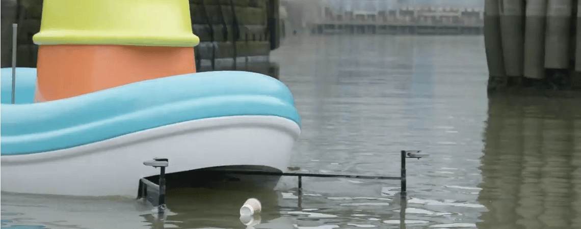 Spielzeugboot fischt Plastikbecher aus der Themse