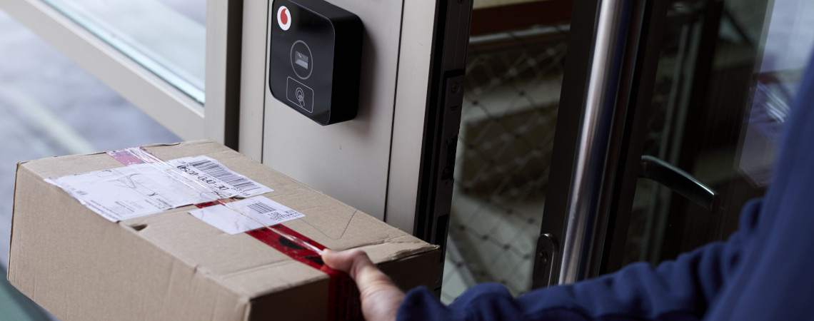 Smarter Türöffner von Vodafone: Mann hält Paket unter smartes Türschloss