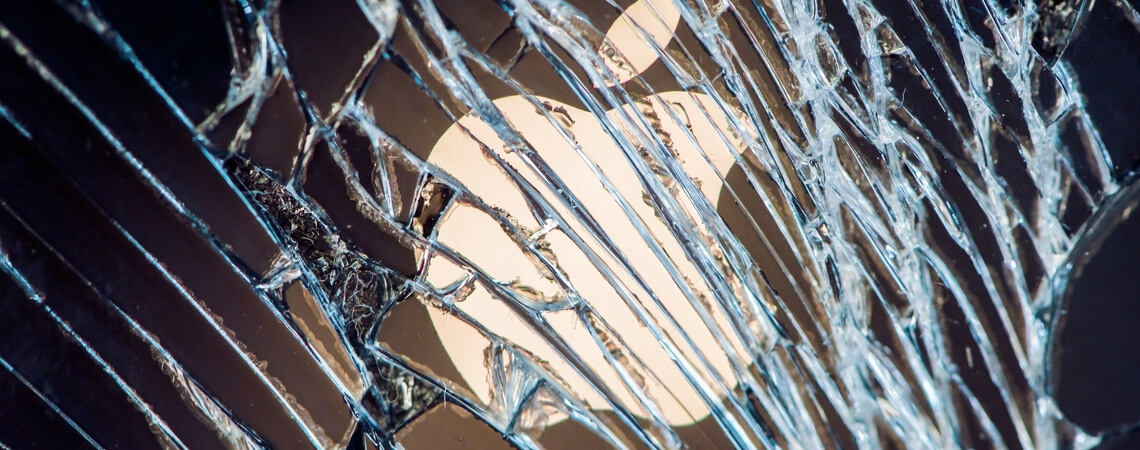 Apple-Logo hinter einer zersplitterten Glasscheibe