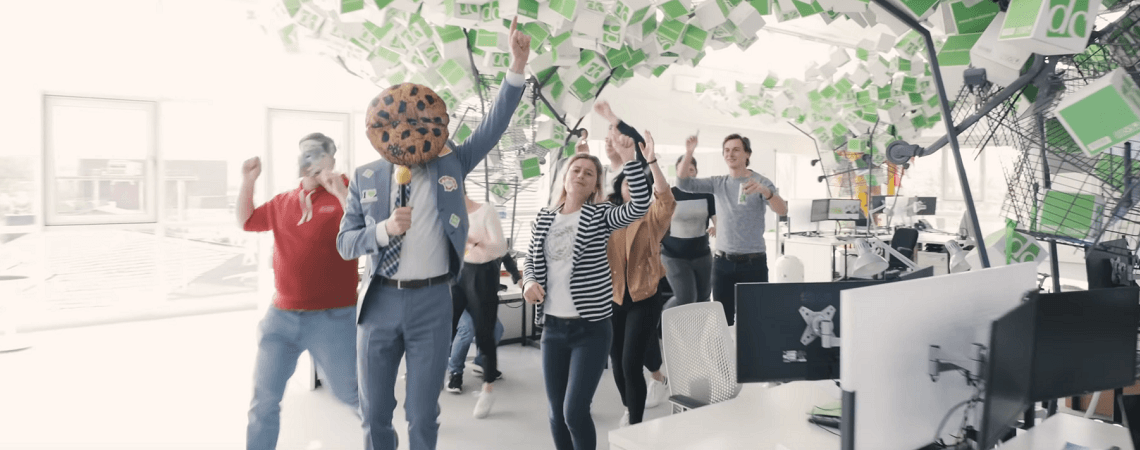 E-Commerce-Agentur Mitarbeiter tanzen, einer mit Keks-Kopf