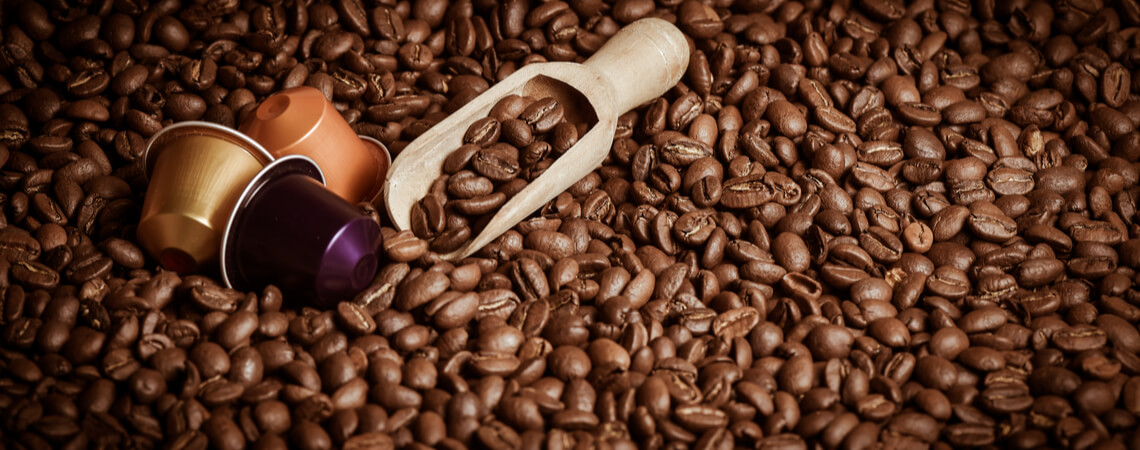 Kaffee-Kapseln liegen auf Kaffee-Bohnen.