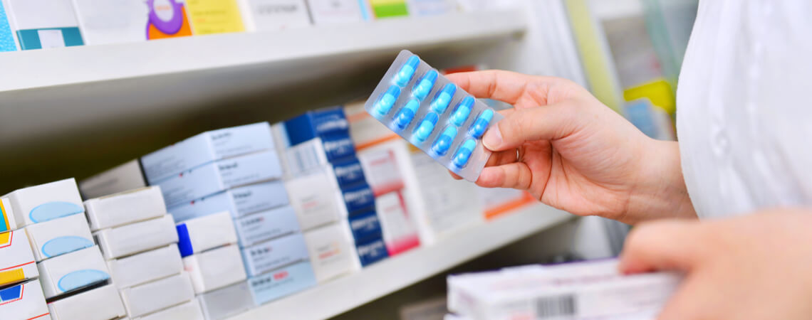 Apotheker nimmt Medikamente aus Regal