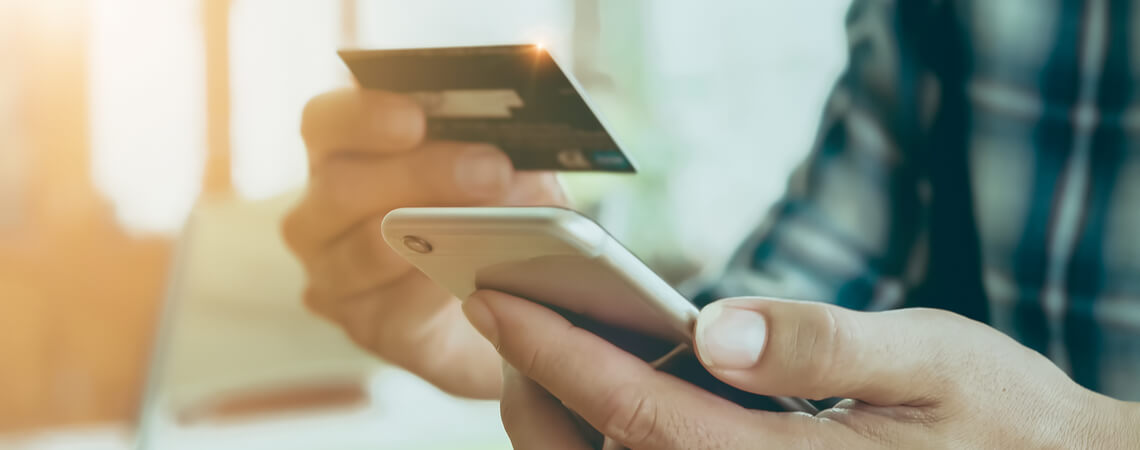Person zahlt online mit Kreditkarte und Smartphone