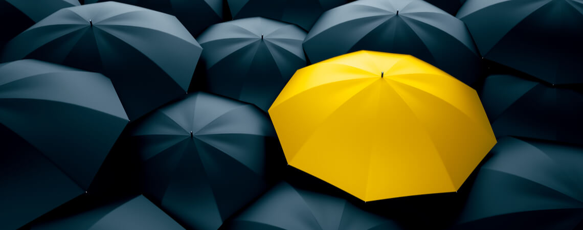 Gelber Regenschirm in einer Menge schwarzer Regenschirme.