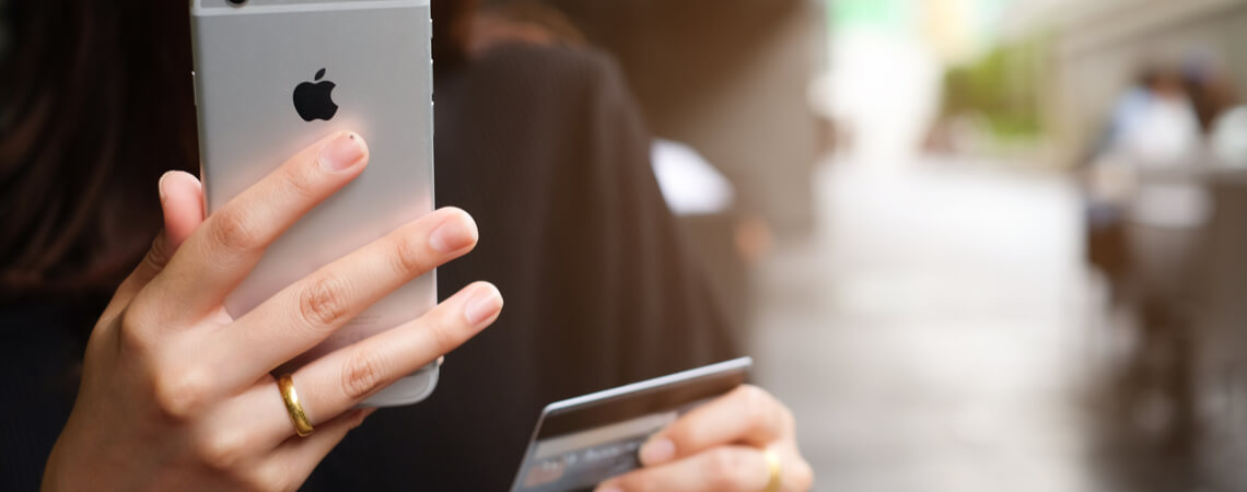 Apple Pay: Frau mit iPhone und Zahlungskarte in der Hand