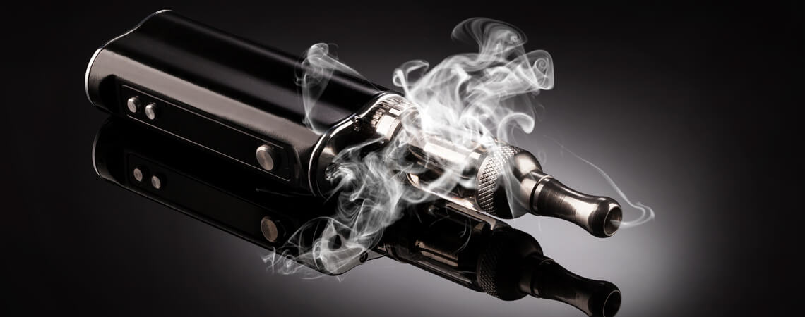 dampfende E-Zigarette vor schwarzem Hintergrund.