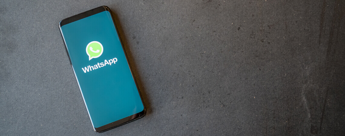WhatsApp-Logo auf einem Smartphone vor grauem Grund