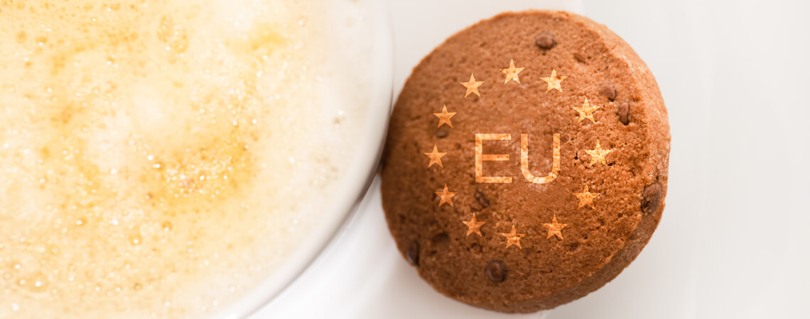 Keks mit der Aufschrift EU und Sternen liegt neben einer Tasse Kaffee
