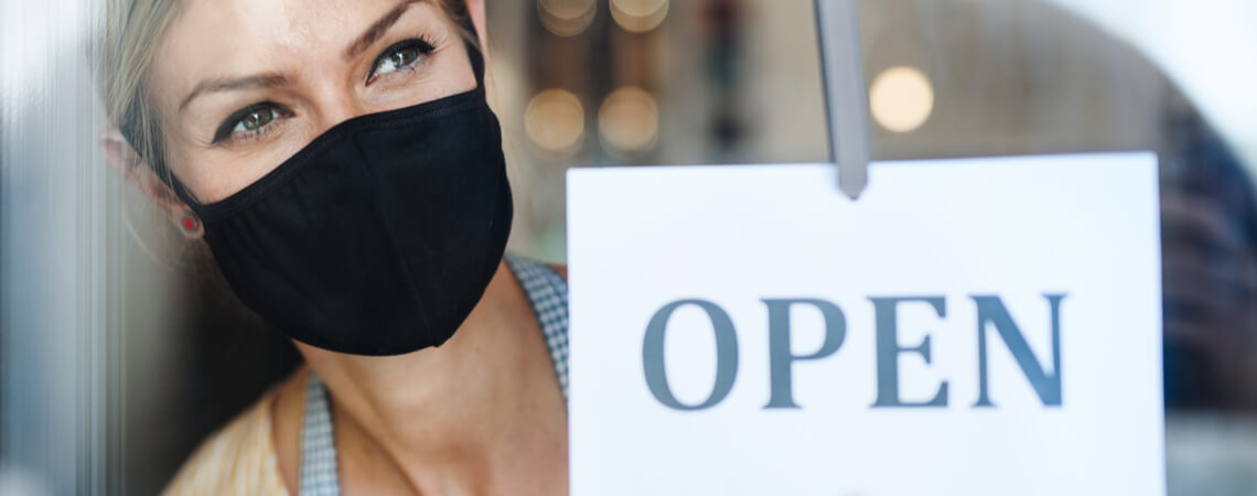 Frau mit Mundschutz geöffneten Laden