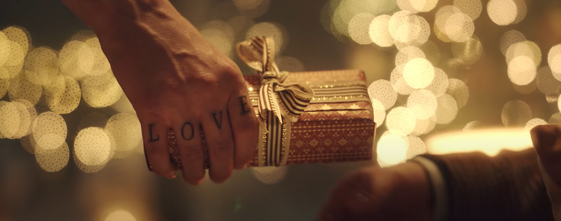 Mann mit Love-Tattoo auf der Hand übergibt Geschenk