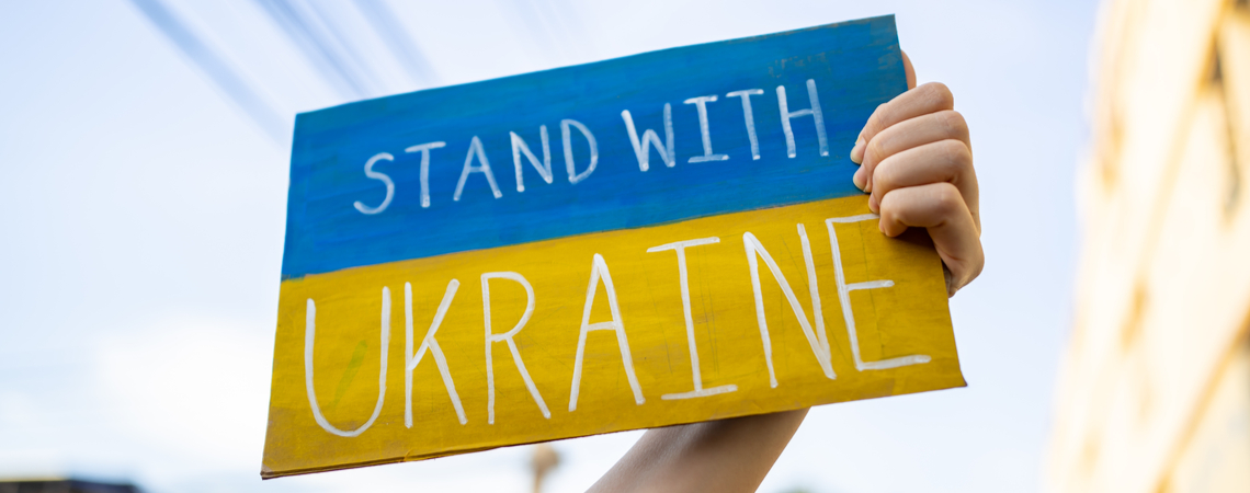 Hand hält "Stand with Ukraine"-Plakat