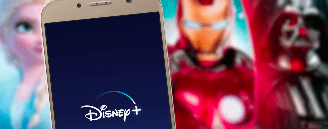 Disney+-App auf einem Smartphone. Streaming-Dienst auf TV dahinter.