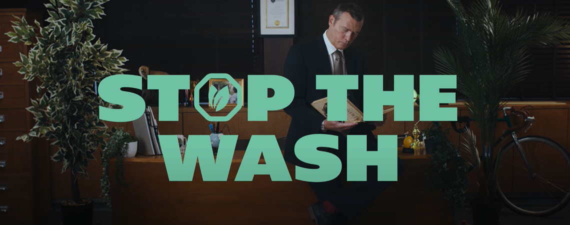 Schriftzug „Stop the Wash“ vor Mann im Anzug hinterm Schreibtisch