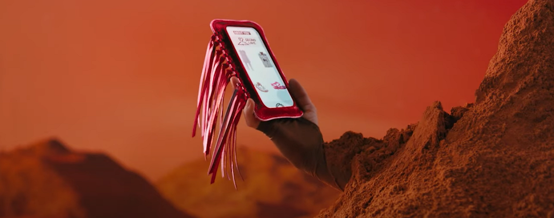 Frau mit rotem Sand bedeckt auf Mars hält Smartphone mit About You