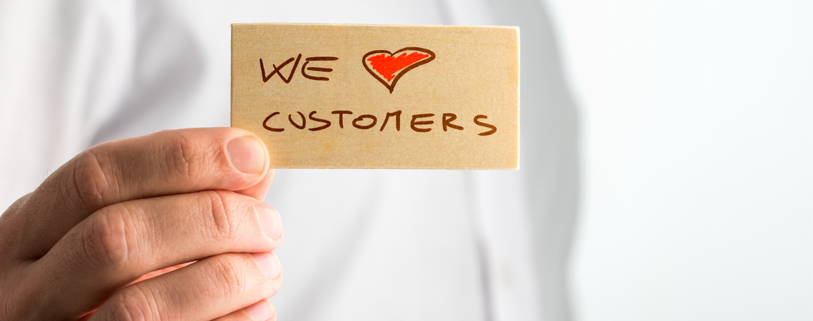 Mann hält Karte „We love Customers“