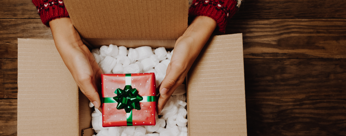 Hände packen Weihnachtsgeschenk in Karton
