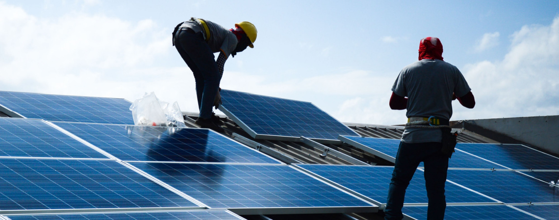 Handwerker installieren Solarmodule auf einem Dach
