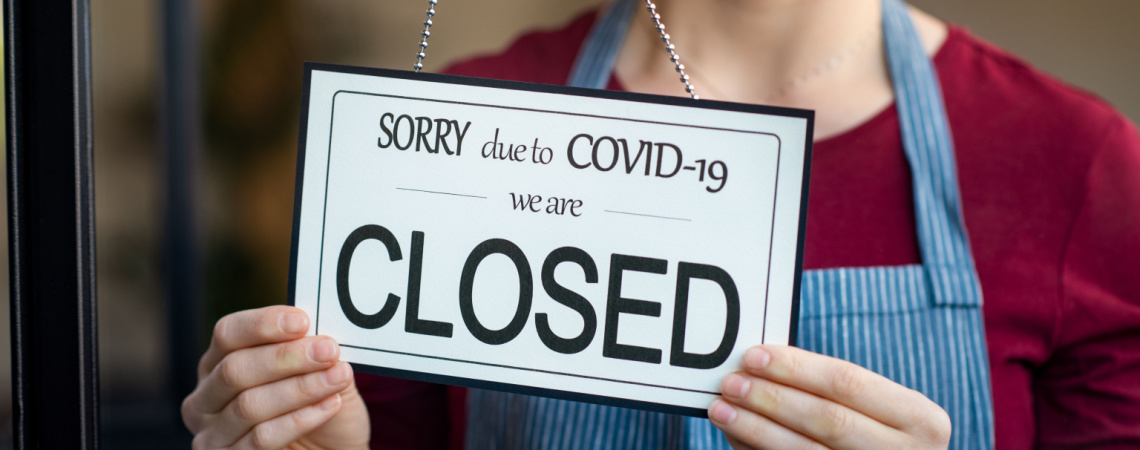 Frau hängt "Closed"-Schild wegen Corvid-19 auf