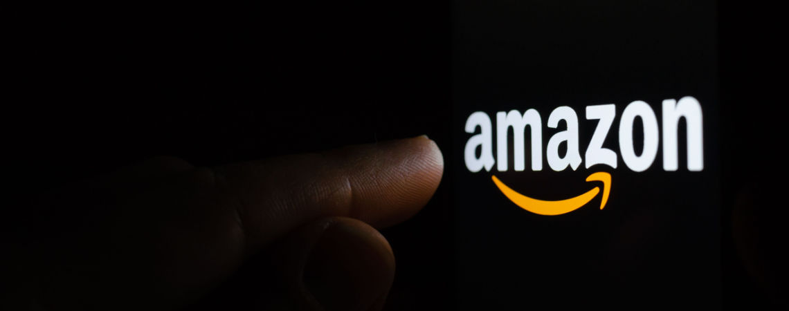 Finger berührt Amazon-Logo dunkler Hintergrund