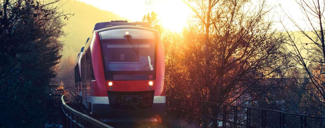 Zug der Deutschen Bahn fährt in den Sonnenuntergang.