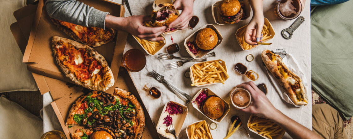 Fastfood-Abendessen vom Lieferdienst: Freunde essen Burger, Pommes und Pizza