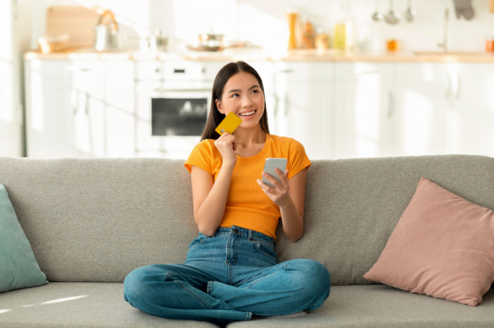Frau auf Sofa mit Kreditkarte