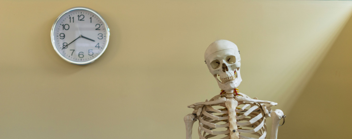 Skelett wartet vor einer Uhr