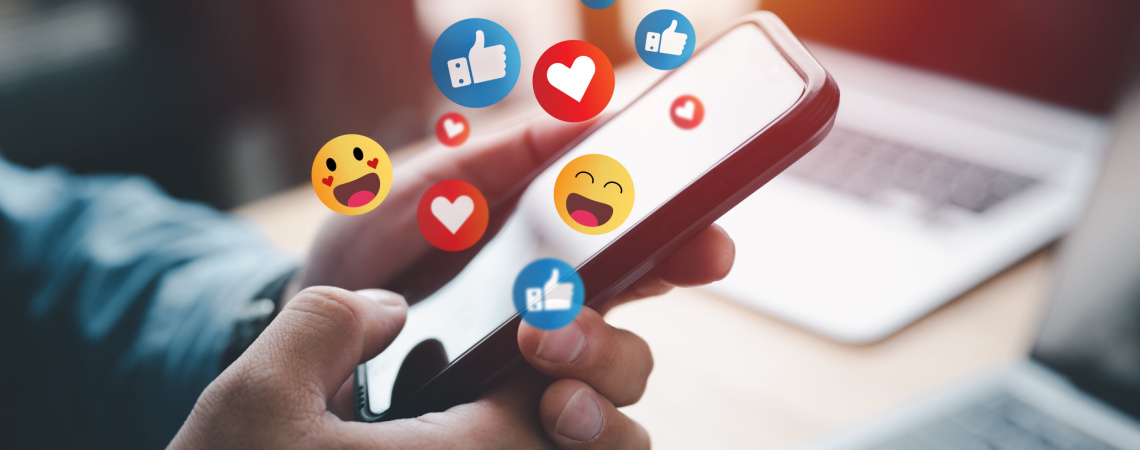 Mensch hält Smartphone Emojis und Social Media Likes