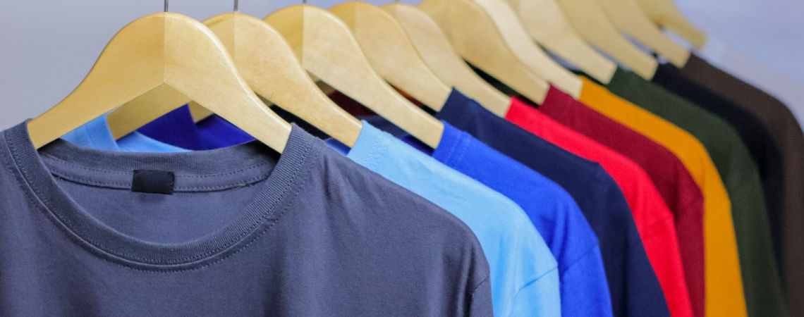 Basic-T-Shirts in verschiedenen Farben hängen hintereinander an einer Kleiderstange