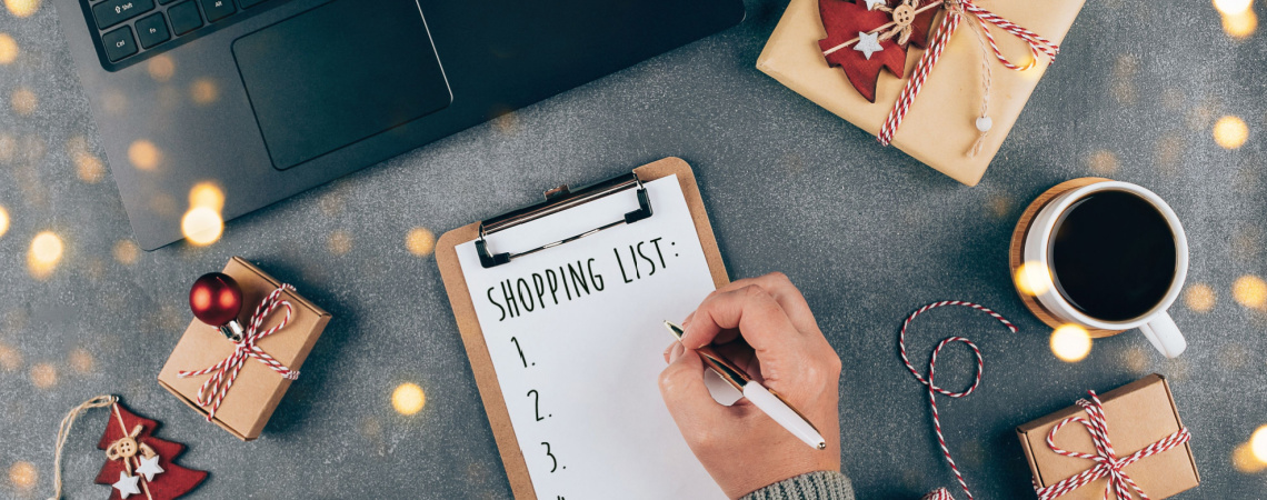 Person am Laptop schreibt Einkaufsliste, Weihnachtspakete drumherum