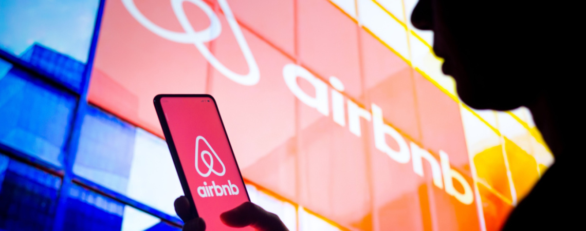 Airbnb-Logo an Gebäude und auf Smartphone