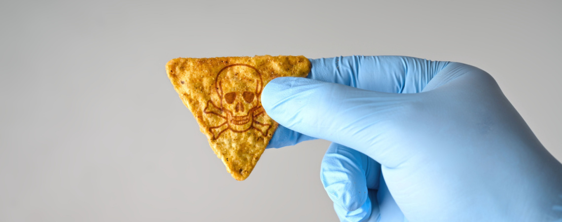 Hand in Gummihandschuh in Labor untersucht Chip mit Totenkopfsymbol drauf