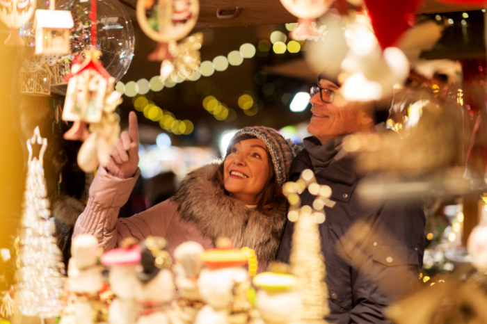 Ehepaar mittleren Alters steht vor Verkaufsstand auf dem Weihnachtsmarkt