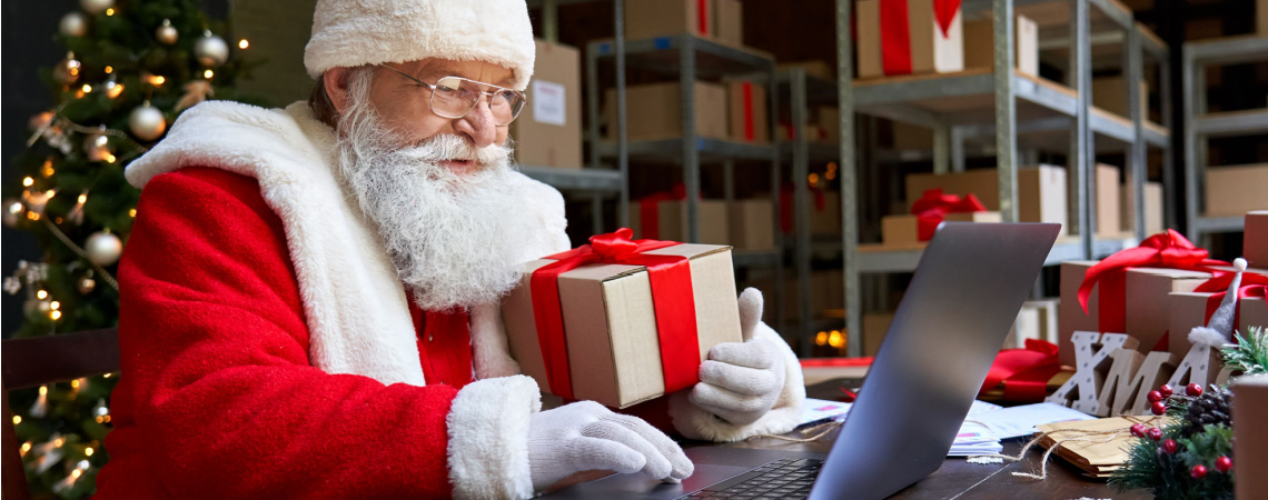 Weihnachtsmann mit Paket vor PC