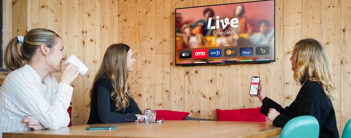Drei Frauen schauen auf Apple-TV mit Otto Live Shopping App