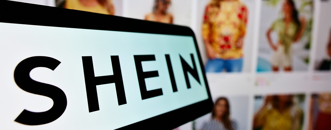 Shein-Logo auf Smartphone vor Website mit Mode