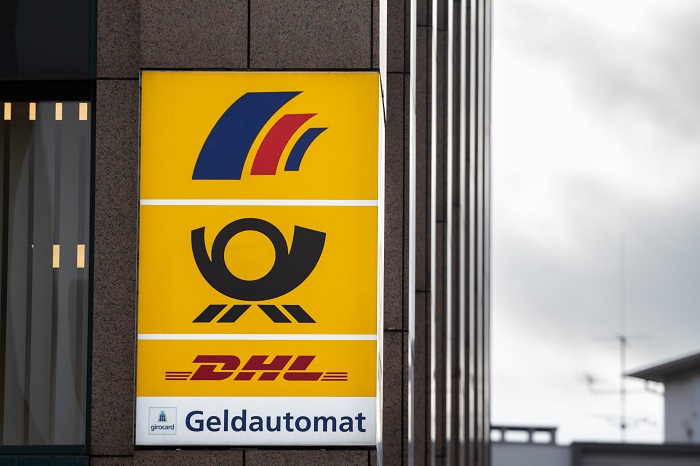 Schild mit Postbank-, Deutsche-Post und DHL-Logo an Hauswand
