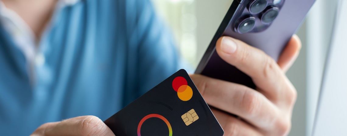 Person hält Kreditkarte und iPhone in den Händen